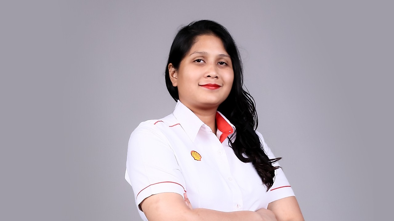 Zahira smiling with hand cross looking at camera wearing white Shell corporate shirt