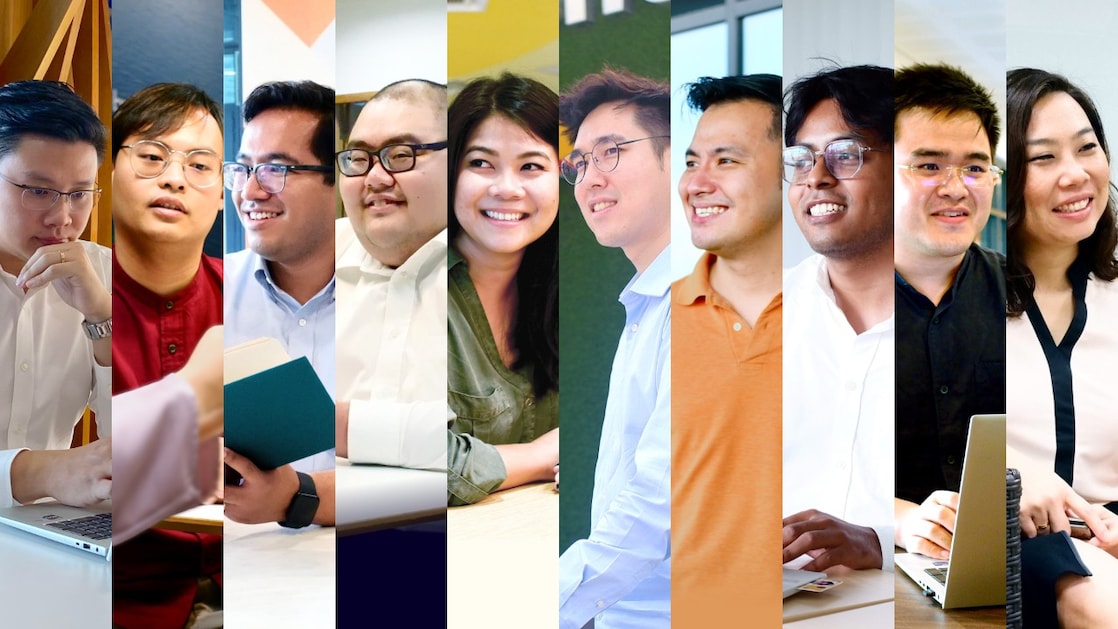 Diverse group of professionals in a vibrant workspace, engaged in various activities with laptops and discussions, dressed in business casual attire.