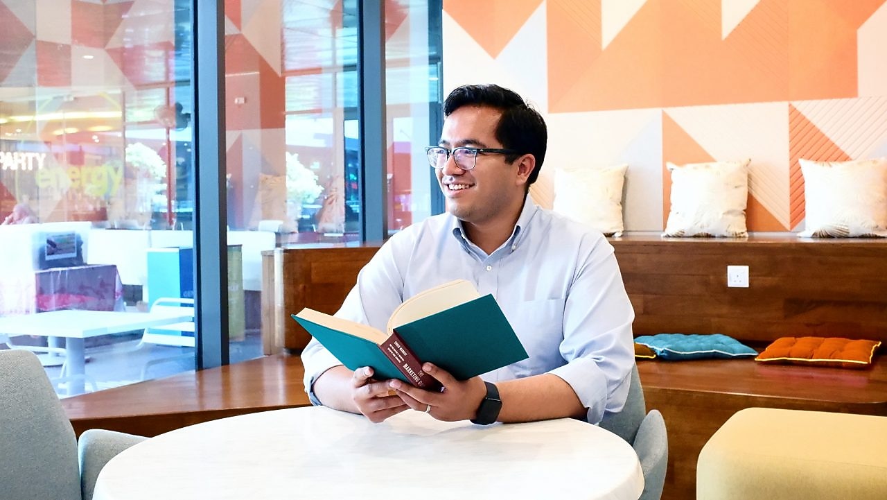 Aflah takes a minute and looks away from the book he is reading.