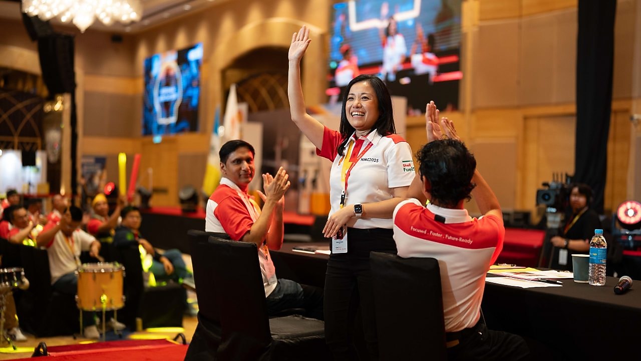 Lee Ming engaging with Shell retailers at the recent Shell National Mobility Conference by having her right hand raised up facing the audience.