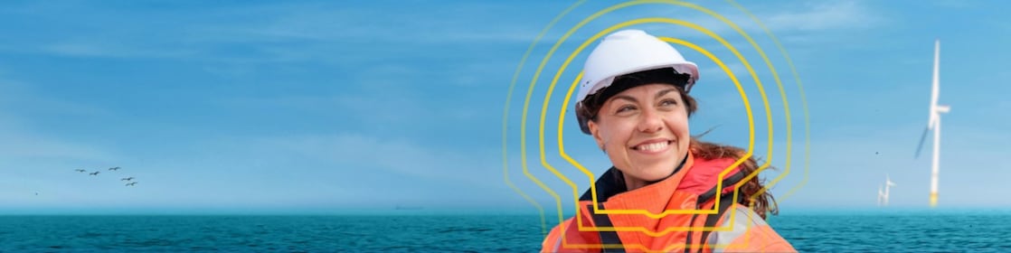 A woman employee in her personal protective equipment near the ocean , smiling.