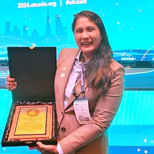 Zahira posing with the awards plate and standing in front of the awards stage