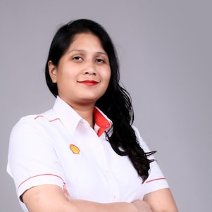 Zahira smiling with hand cross looking at camera wearing white Shell corporate shirt