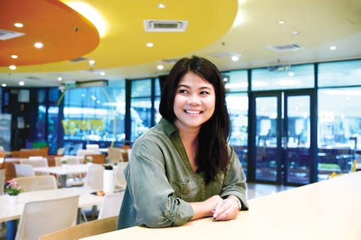 Claris looks away and smiles while she is at the cafetria at office.