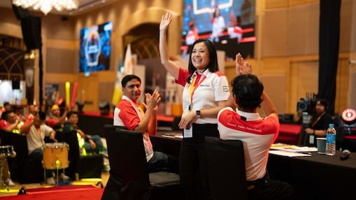 Lee Ming engaging with Shell retailers at the recent Shell National Mobility Conference by having her right hand raised up facing the audience.
