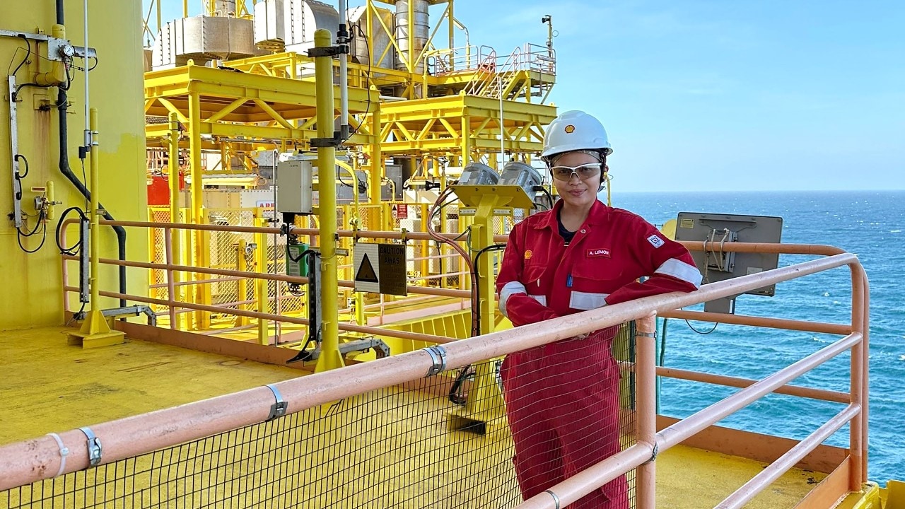 A female engineer at an offshore site equipped with coveralls and a safety helmet.