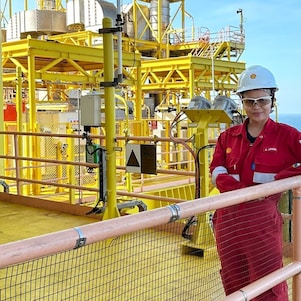 A female engineer at an offshore site equipped with coveralls and a safety helmet.