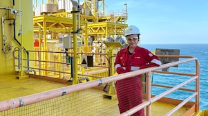 A female engineer at an offshore site equipped with coveralls and a safety helmet.