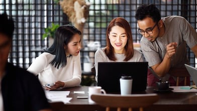 Three people looking at a laptop
