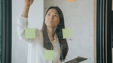 A woman placing post its on a glass wall