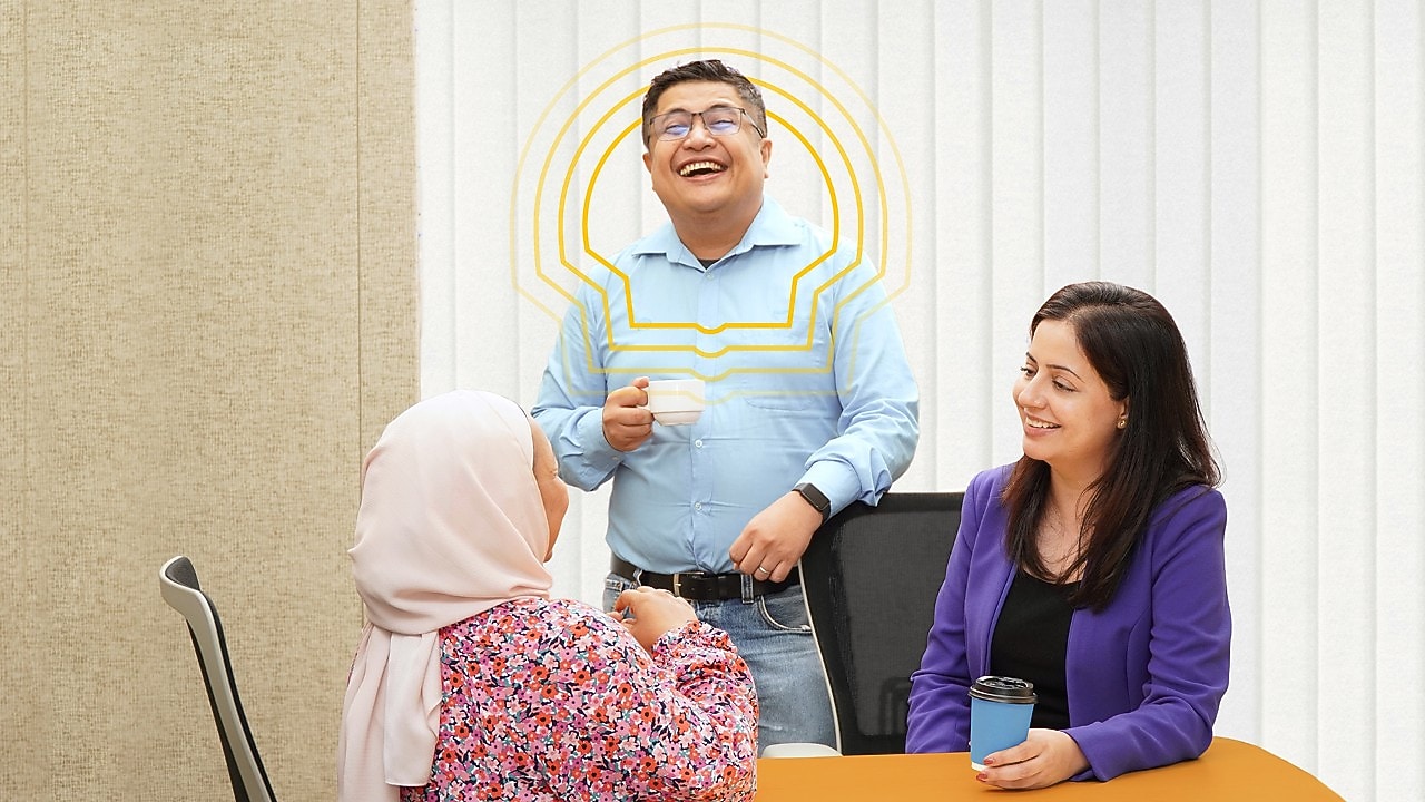 an employee standing is having an engaging conversation with his colleagues who are seated.