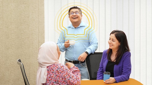 an employee standing is having an engaging conversation with his colleagues who are seated.