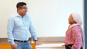 Two employees standing across each other and having a conversation with each other.