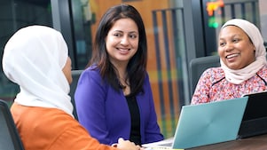 an employee standing is having an engaging conversation with his colleagues who are seated.