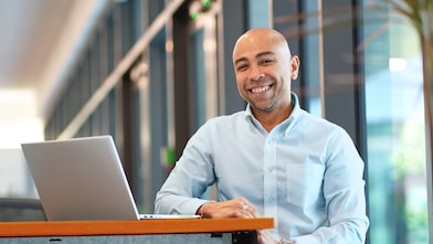 Derrick smiling while his laptop is in front of him