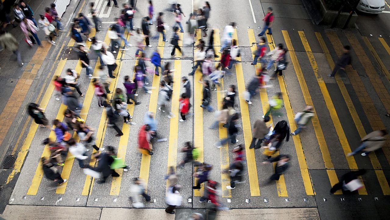 People cross a busy street in Hong Kong