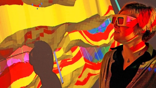 A woman with special goggles examines a 3D wall projection of a geological map