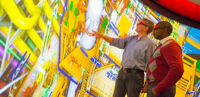 Two men use 3D glasses to look at a large colourful screen