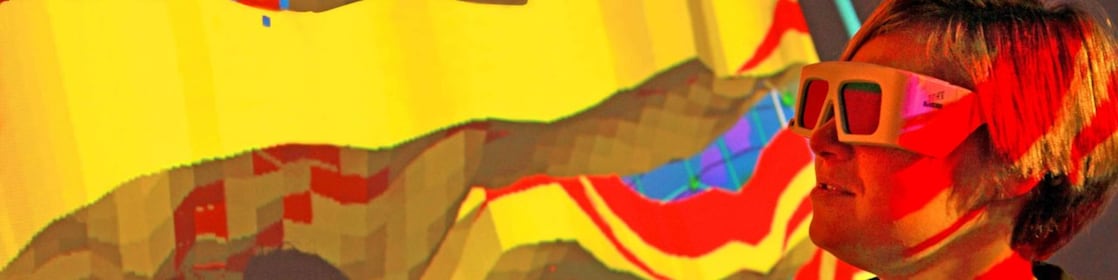 A woman with special goggles examines a 3D wall projection of a geological map