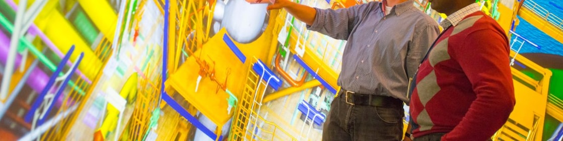 Two men use 3D glasses to look at a large colourful screen