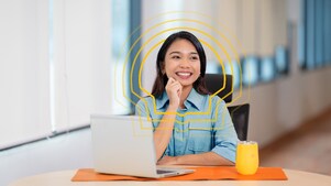 female employee sitting at a table with her hand on her chin and smiling