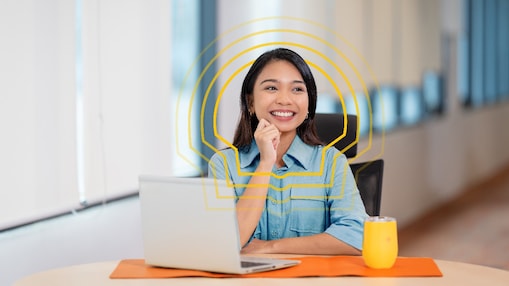 female employee sitting at a table with her hand on her chin and smiling
