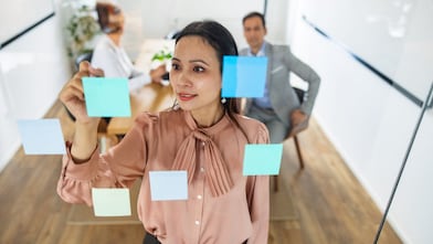 A woman placing post its on a glass wall