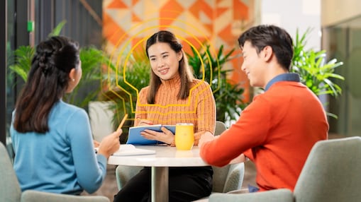 three employees seated at a table and having a work related discussion