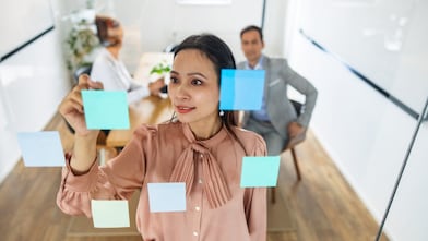 A woman writing placing post-its on a glass wall