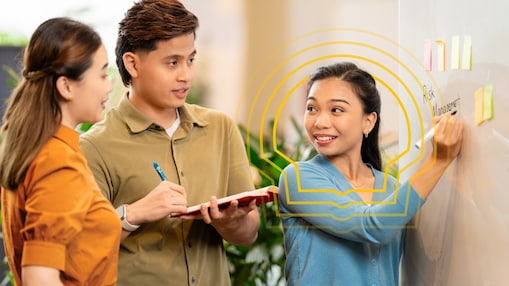 three employees working together at work and using the white board