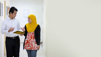 Employees walking and talking in corridor with iPad