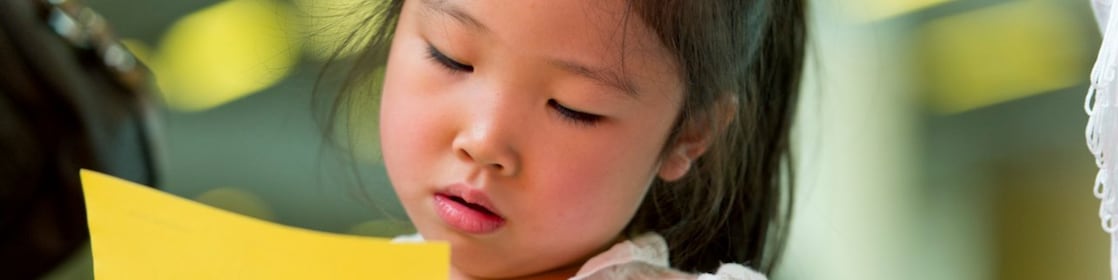 Young girl cutting paper with scissors.