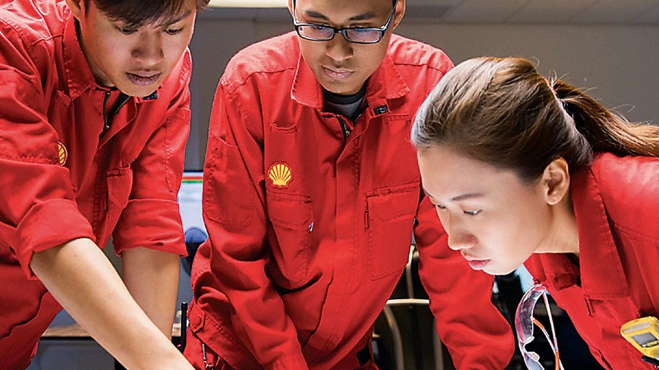 three people looking at plans red uniforms