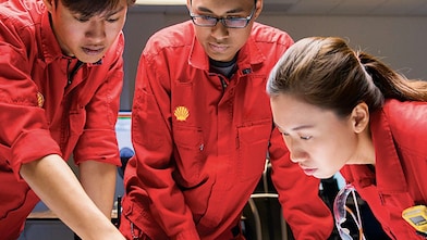 three people looking at plans red uniforms