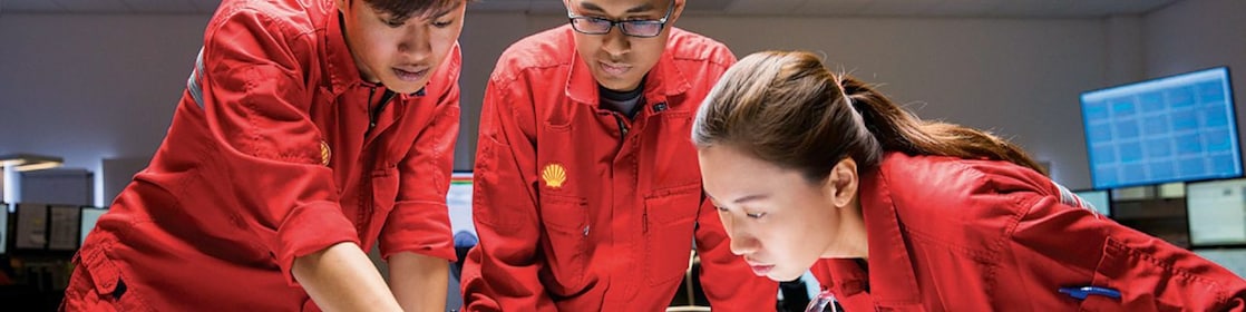 three people looking at plans red uniforms
