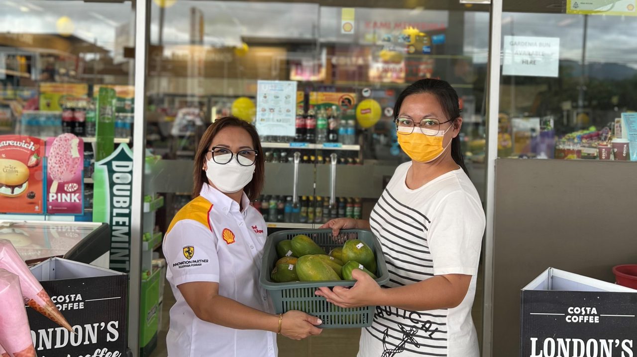Juliana assisting a housewife in selling her papayas in her station