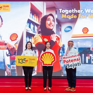 Shell Malaysia team members stand on stage holding anniversary and brand placards, set against a large backdrop celebrating 135 years and the “Together, We Are Made for More” message.