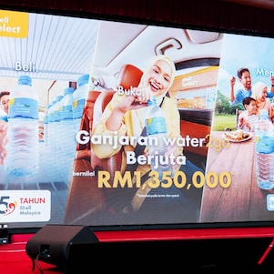 A presentation screen highlights the “Ganjaran water2go Berjuta” campaign and RM1.35 million in prizes, as a Shell representative presents the initiative on stage.