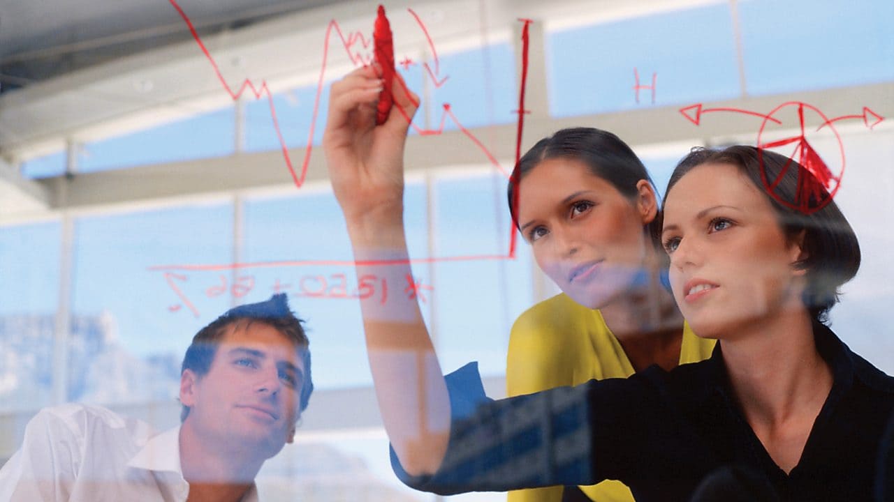 Businesswoman drawing graphs on glass