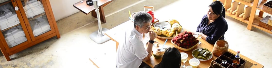 Three people are having a discussion at a table while having breakfast