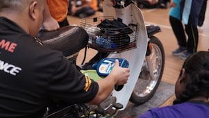 Shell Advance team pouring Shell Advance AX7 lubricant into Honda EX5 motorcycle during product demonstration.
