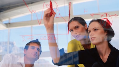 Businesswoman drawing graphs on glass