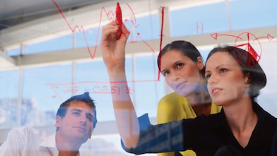 Businesswoman drawing graphs on glass