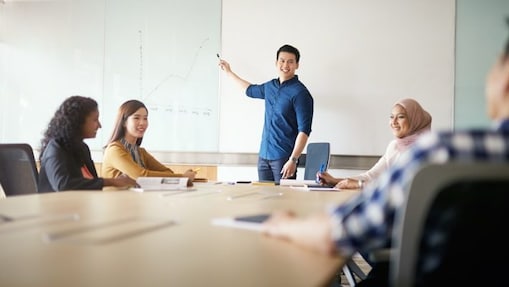 Blue shirt man presenting and pointing towards board