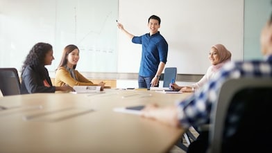 Blue shirt man presenting and pointing towards board