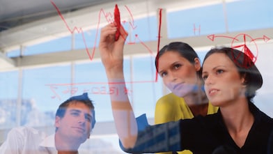 Businesswoman drawing graphs on glass