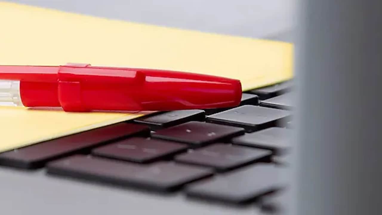 Pen and paper on a laptop