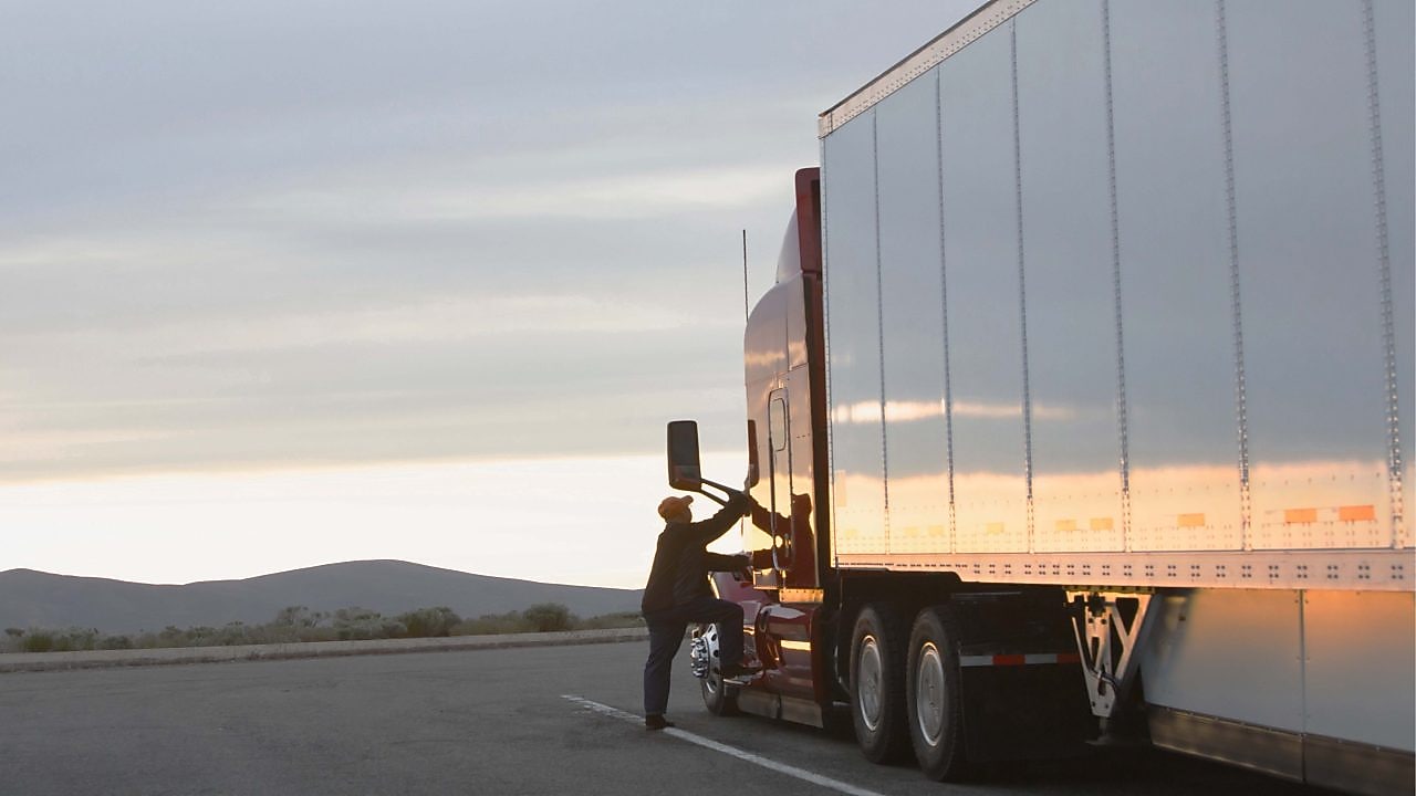 Truck driver climbing into cabin