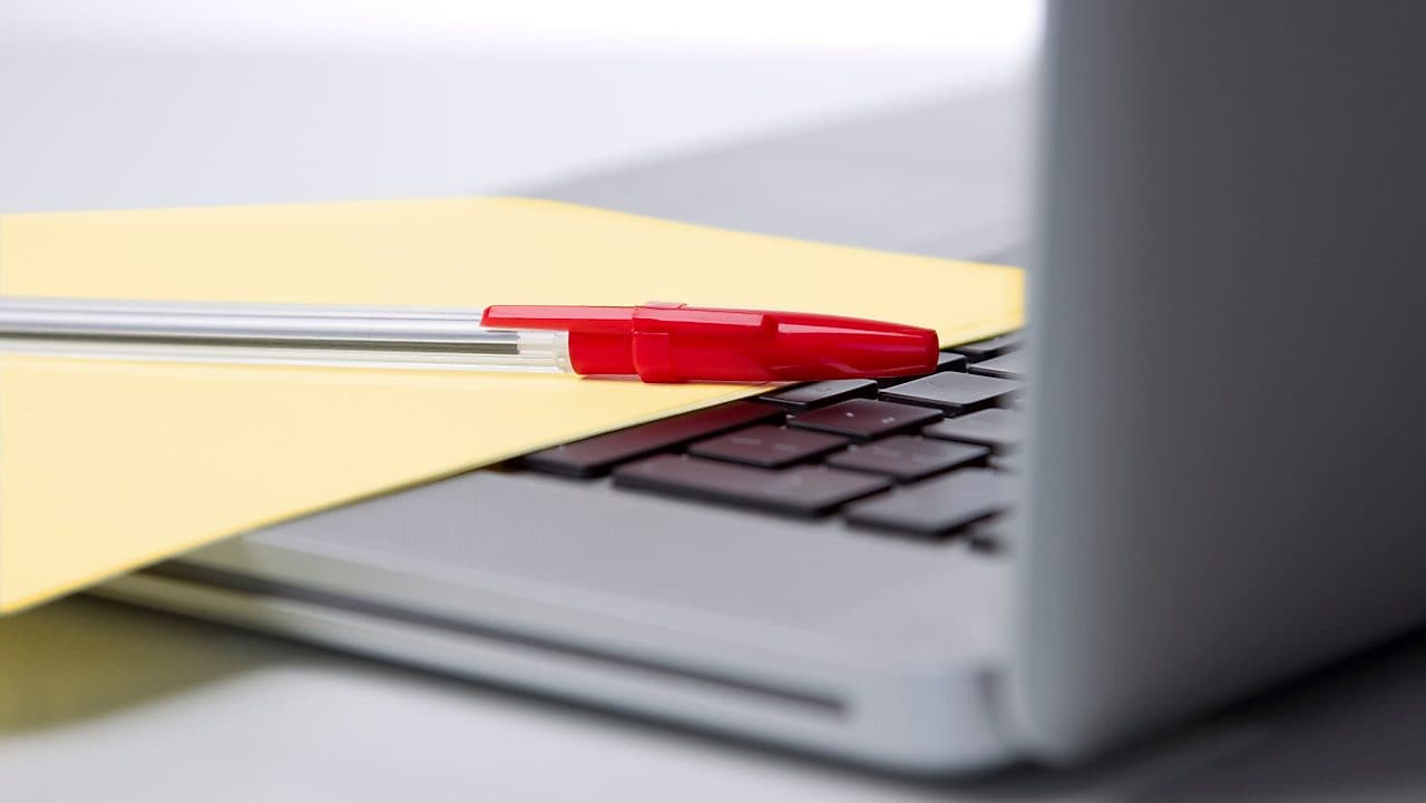 Pen and paper on a laptop