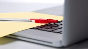 Pen and paper on a laptop